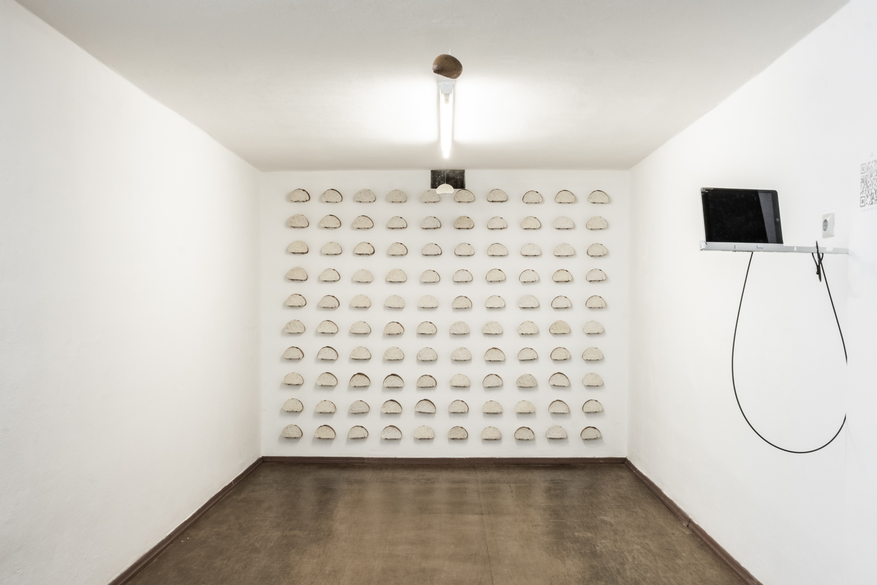 흰색 벽의 공간을 촬영한 이미지로 마주보는 정면의 벽에는 백개의 빵모양의 작업이 설치되어 있다. 천장의 형광들을 기준으로 두개의 빵 끝부분이 매달려 있으며 정면의 벽에서 거리를 두고 오른벽에는 아이패드가 놓여져 있다. 바닥은 나무색의 타일로 깔려 있으며 약간의 광이 난다.