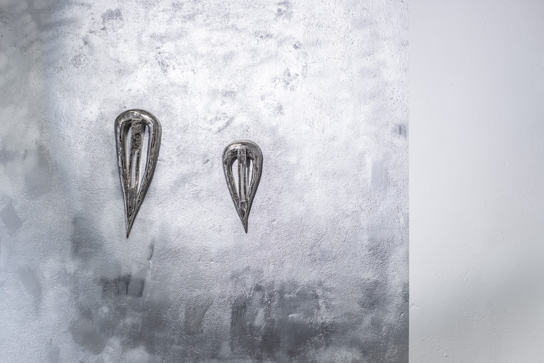 벽의 일부가 네모난 은색으로 칠해져 있으며 그 중앙으로 헤어핀 모양의 도자 작업이 놓여져 있다. 도자작업 또한 광이 나는 은색이다.